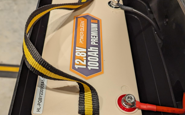 Power Queen 12v 100ah deep cycle battery pack with '12.8V 100Ah Premium' label and yellow strap.