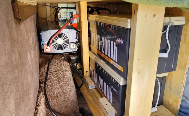 Power Queen 12v 200ah plus lifepo4 batteries inside a wooden cabinet