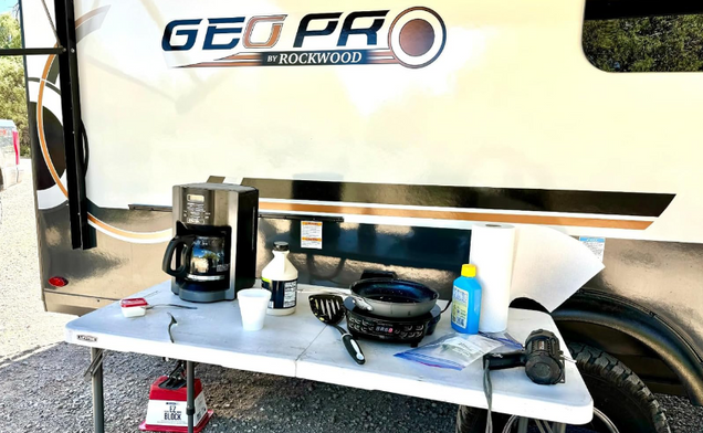 Portable table with coffee maker and bottles in front of Rockwood RV powered by Power Queen 12V Lithium LiFePO4 Batteries