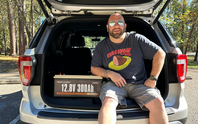 Person sitting in the open trunk of a car with Power Queen 12v 300ah lithium battery