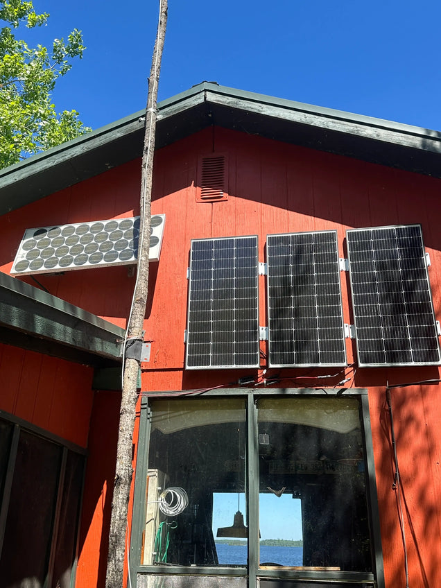 Off-grid solar panel installation on a lakeside cabin using Power Queen lithium batteries.