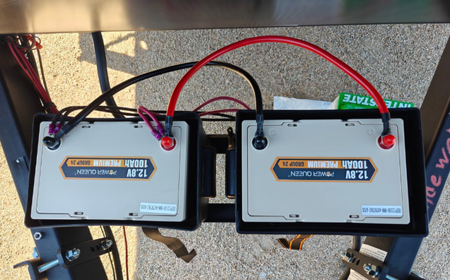 Two 12v 100ah Lithium LiFePO4 battery packs with visible labels on a concrete surface.