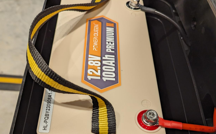 Power Queen 12v 100ah deep cycle battery pack with '12.8V 100Ah Premium' label and yellow strap.