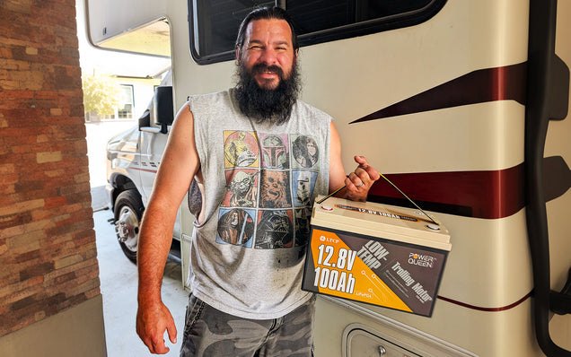 Man holding a Power Queen lifepo4 deep cycle battery pack in front of an RV