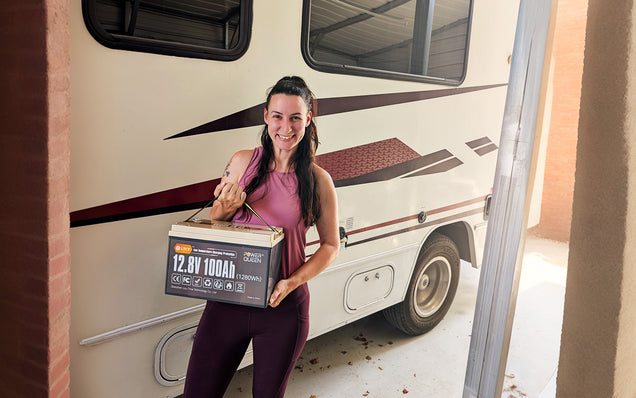 Woman holding a lifepo4 deep cycle battery pack in front of an RV