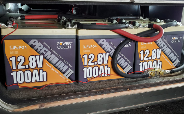 Three Power Queen 12V Lithium LiFePO4 Batteries with visible specifications on a dark surface.