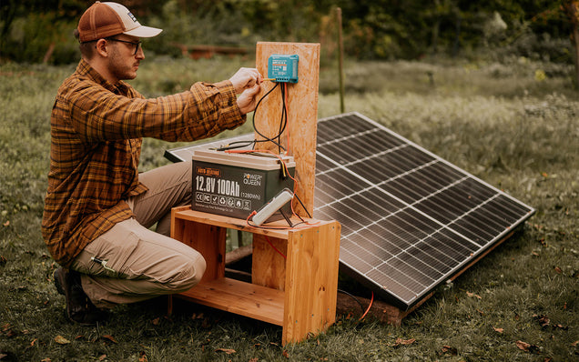 Man tests a 12v 100ah deep cycle battery on a solar panel setup outdoors