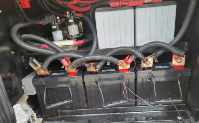 Power Queen 12V Lithium LiFePO4 Batteries pack with cables and connectors in a vehicle's storage area