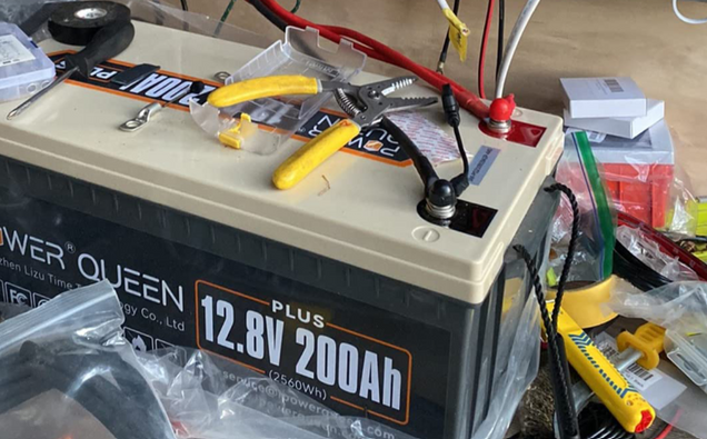 Power Queen 12v 200ah plus lifepo4 battery with cables and tools on a table