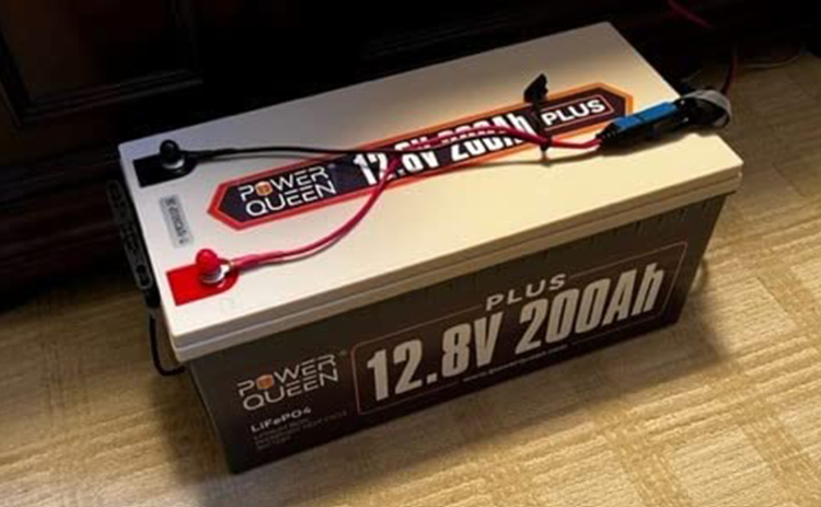 Power Queen 12v 200ah plus lifepo4 battery with specifications on a wooden surface