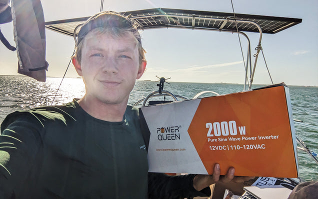 Person holding a Power Queen power 2000w inverter on a boat with sea in the background