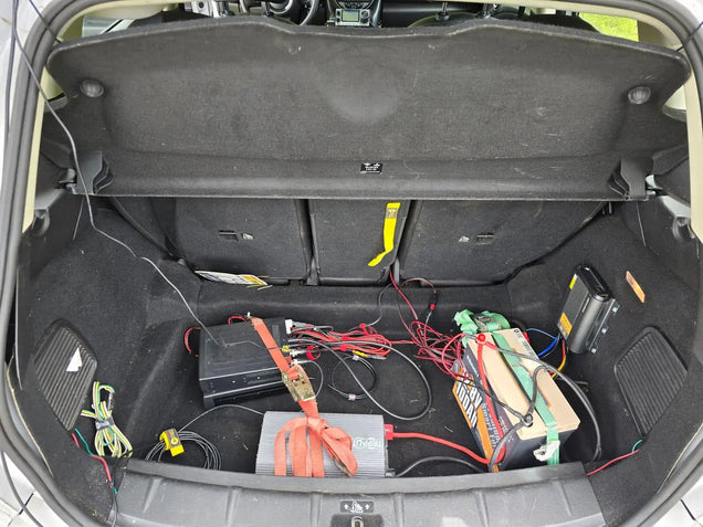 Open car trunk with electrical equipment like Power Queen dc to dc battery charger and wires inside
