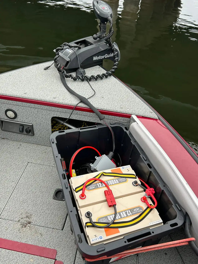 MotorGuide trolling motor attached to a boat with batteries visible as well as Power Queen 12v LifePO4 battery charger. 
